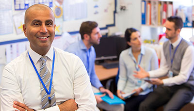 Education administrator standing in front of a group of teachers talking.